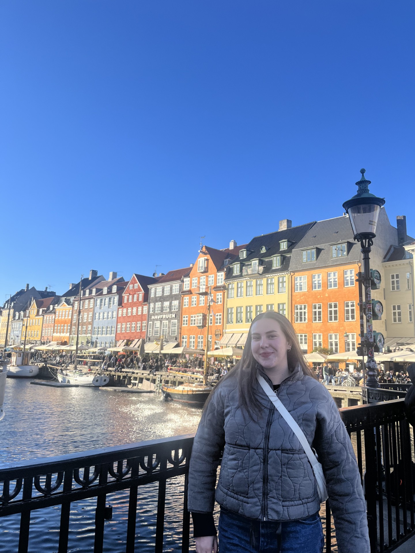 Girl standing on a bridge in front of colourful buildings