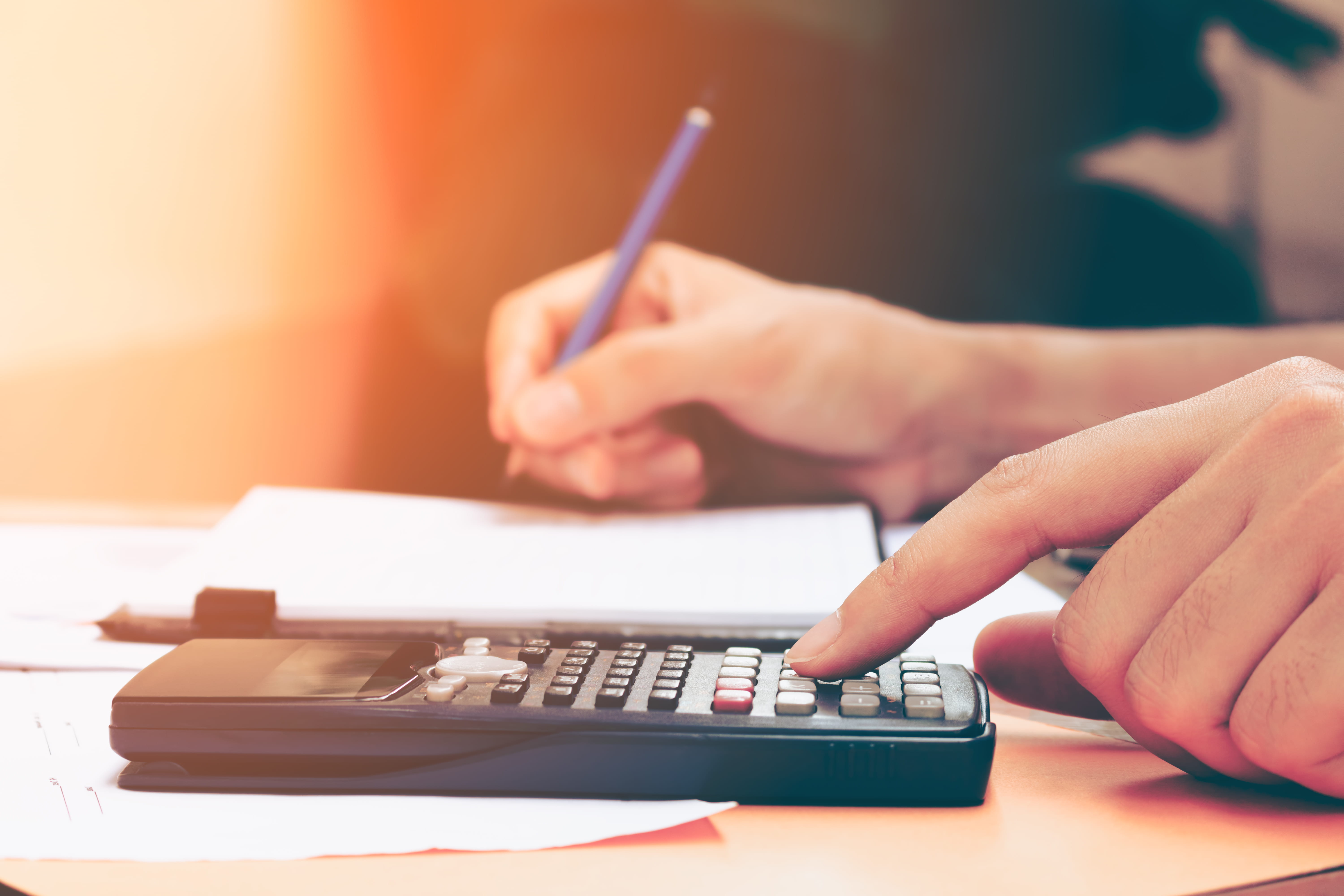 Person using a calculator and a notebook to budget