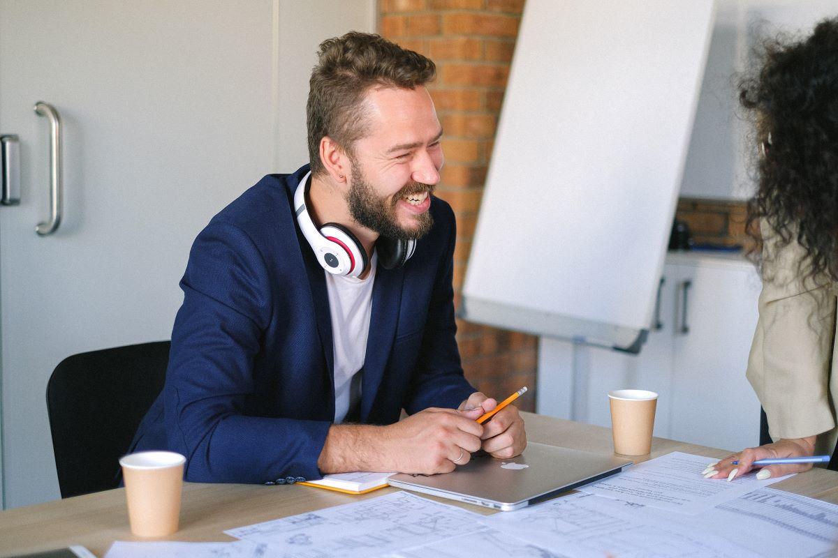 male student talking to other student both laughing over coffee looking at papers