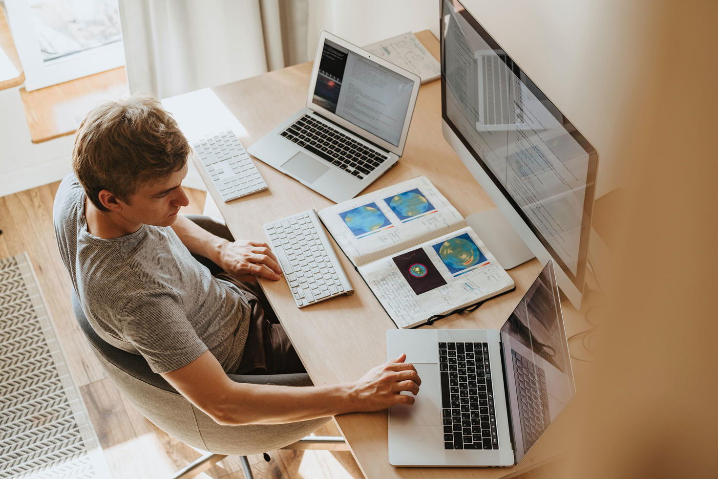 man with laptop with monitor and book and separate computer 