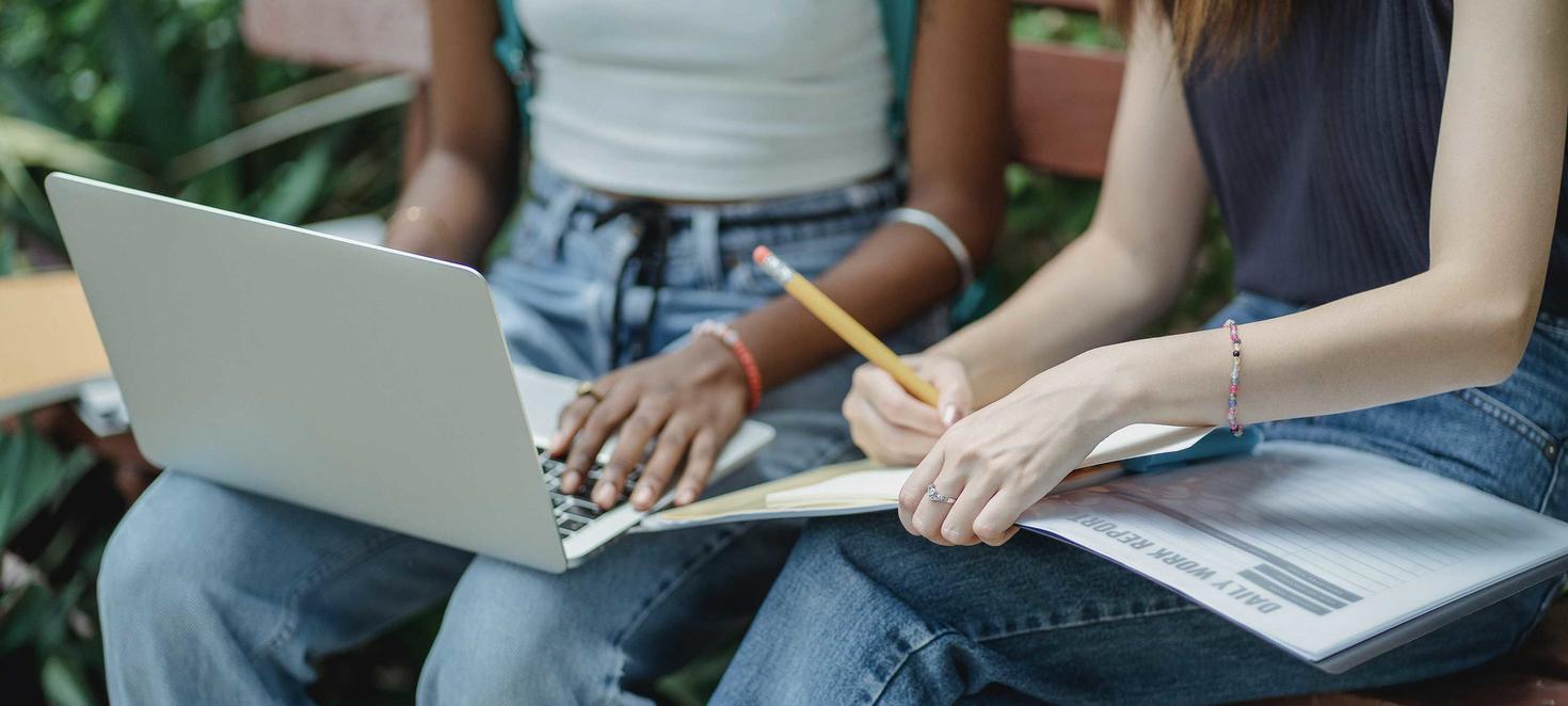 students on a laptop and writing in a book
