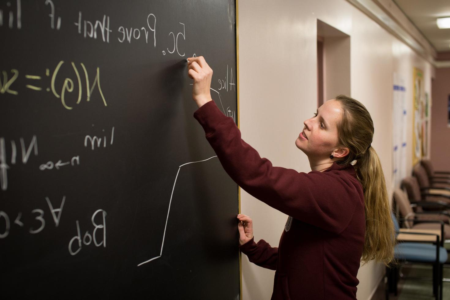 female student writing on blackboard