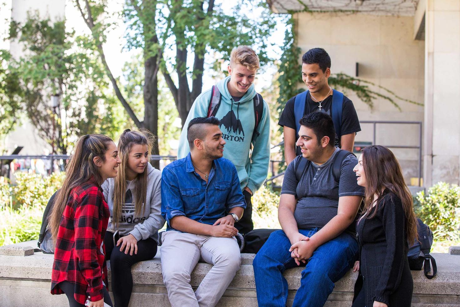 group of happy students sitting outside together