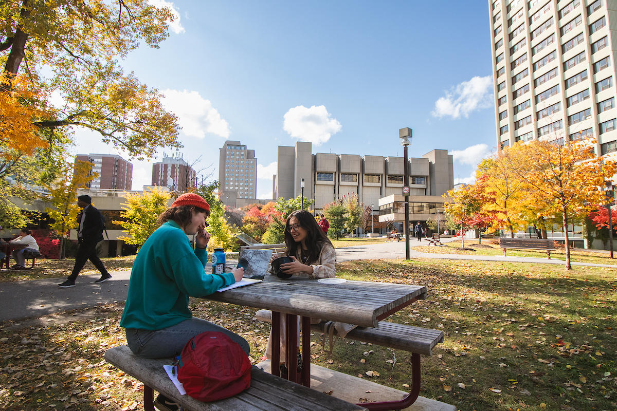 Two students sitting on picnic table.