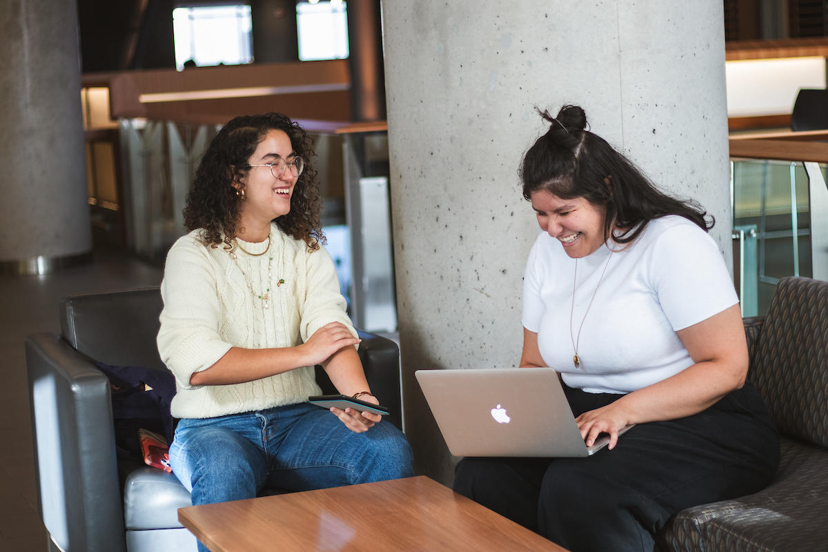 Students laughing and studying in campus building.