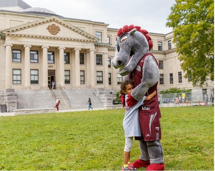 Gee-gee mascot hugging a child