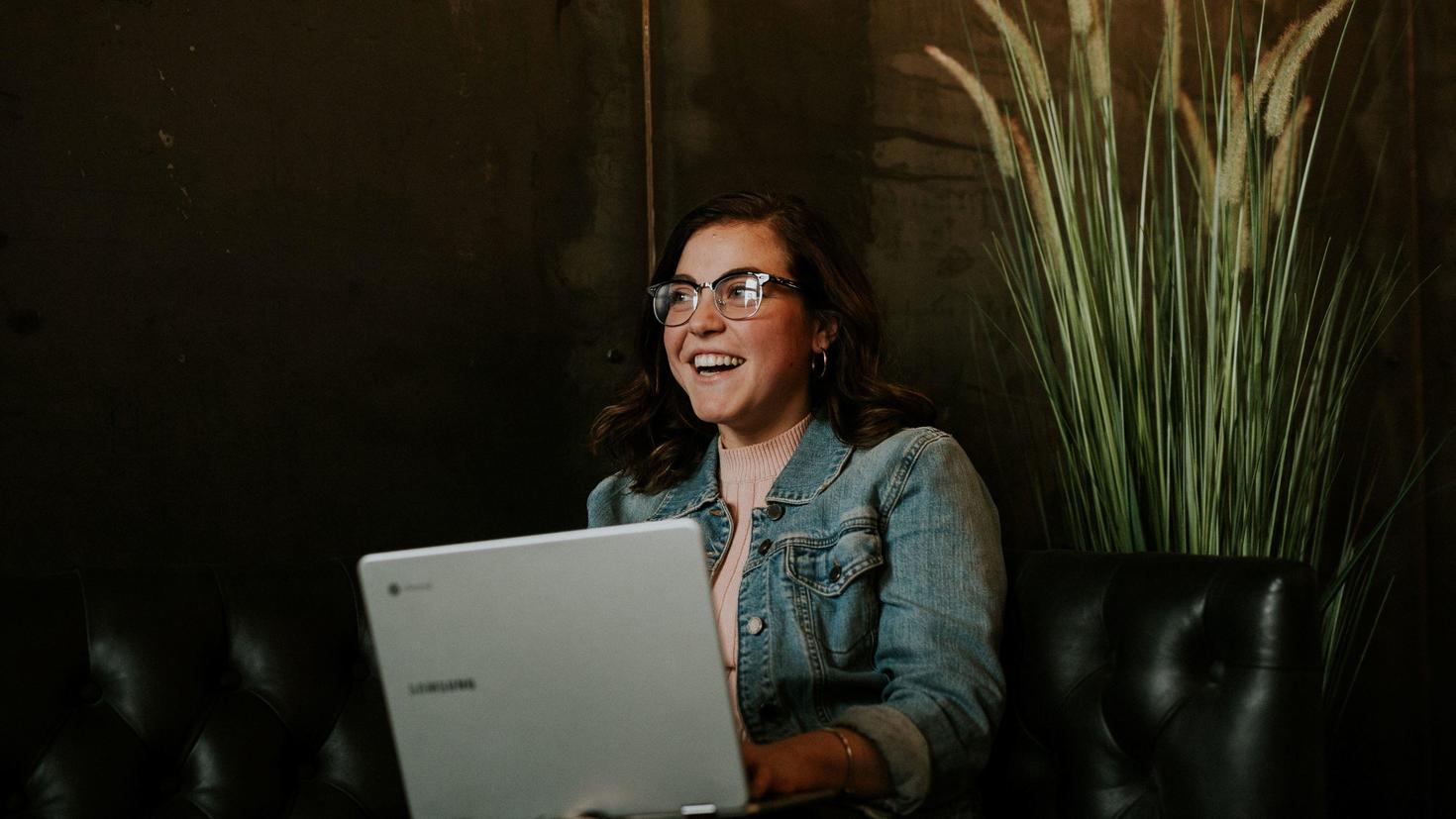 smiling student sitting on a sofa with a laptop