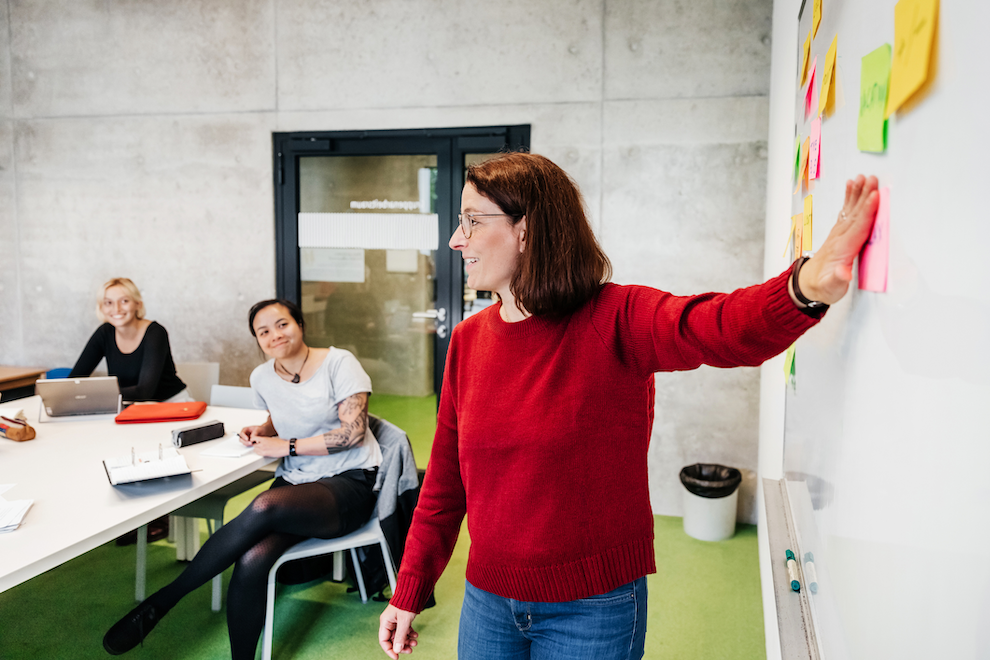 Person teaching small group using post-it notes and whiteboard