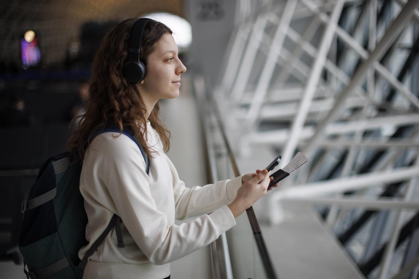 Girl with headphones looking out airport window