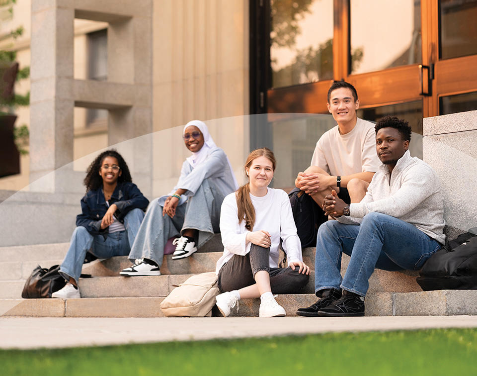 Group of students sitting on the steps of Simard Hall