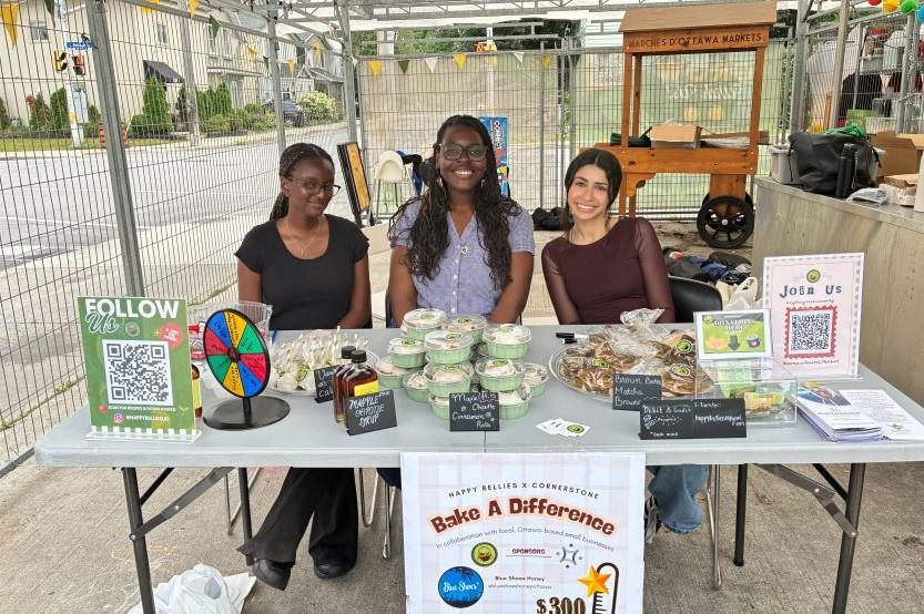 Three student members of the Happy Bellies club sit at a table during a previous Club Fair.