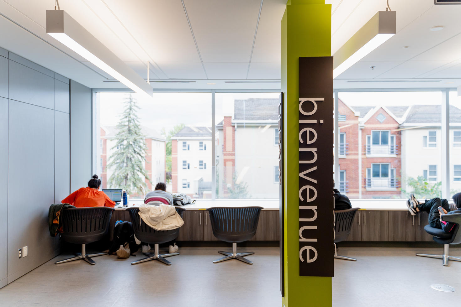 Students studying in front of a window with a pillar saying "bienvenue" (welcome)