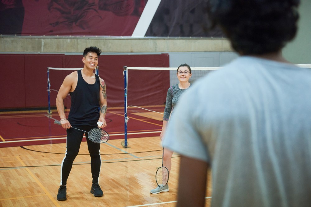 Des gens attendent et sourient sur un terrain de badminton.