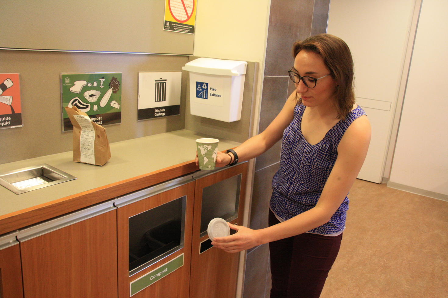 Une employée dépose ses déchets dans un bac à compost sur le campus