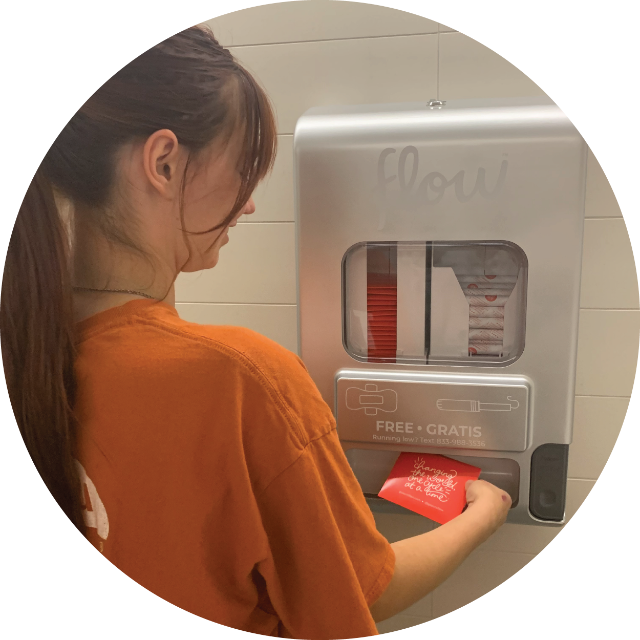 une élève prend un produit menstruel dans un distributeur