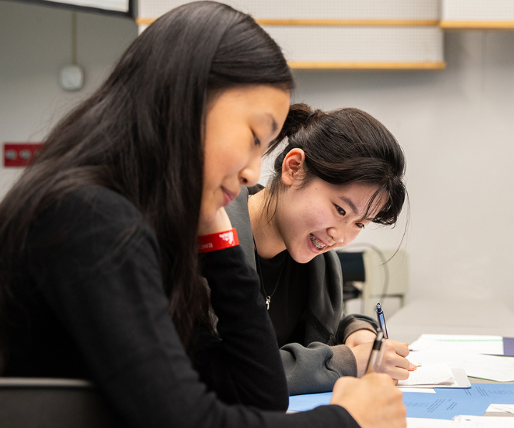 Deux jeunes sont assis à une table et solutionnent un problème mathématique lors du camp de mathématiques 2024 de l’Université d’Ottawa.