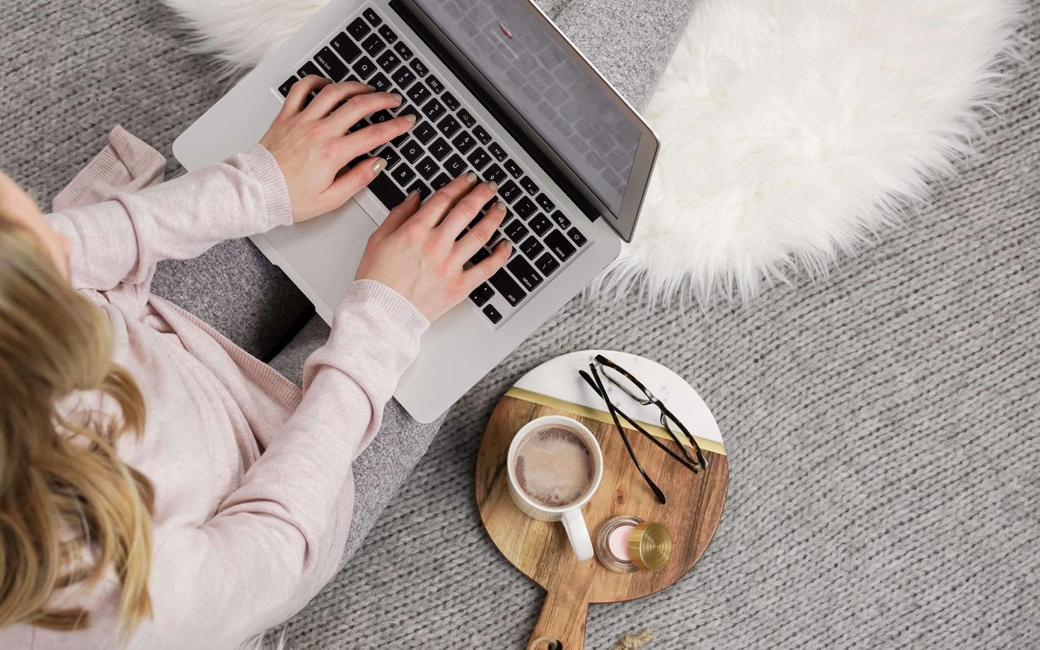 Une femme utilisant son ordinateur avec une tasse à côté d'elle. 