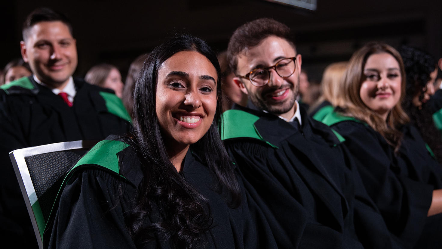 Une étudiante et un étudiant sont assises dans le public lors de la cérémonie de remise des diplômes.