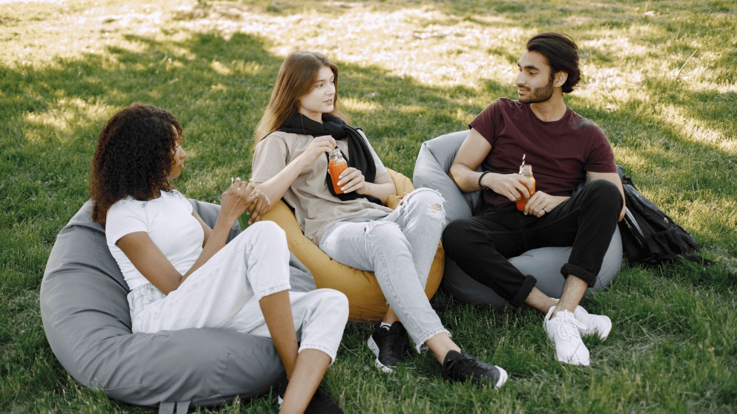 Trois étudiants assis sur des fauteuils poire entrain de discuter, buvant une boisson.