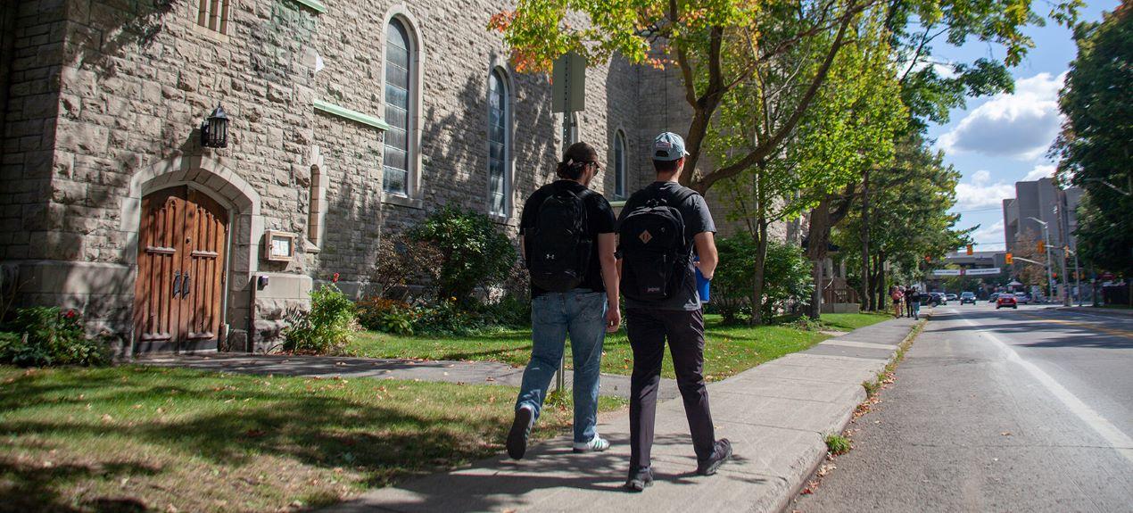 Deux étudiants passent devant une église dans le quartier verdoyant de Sandy Hill.