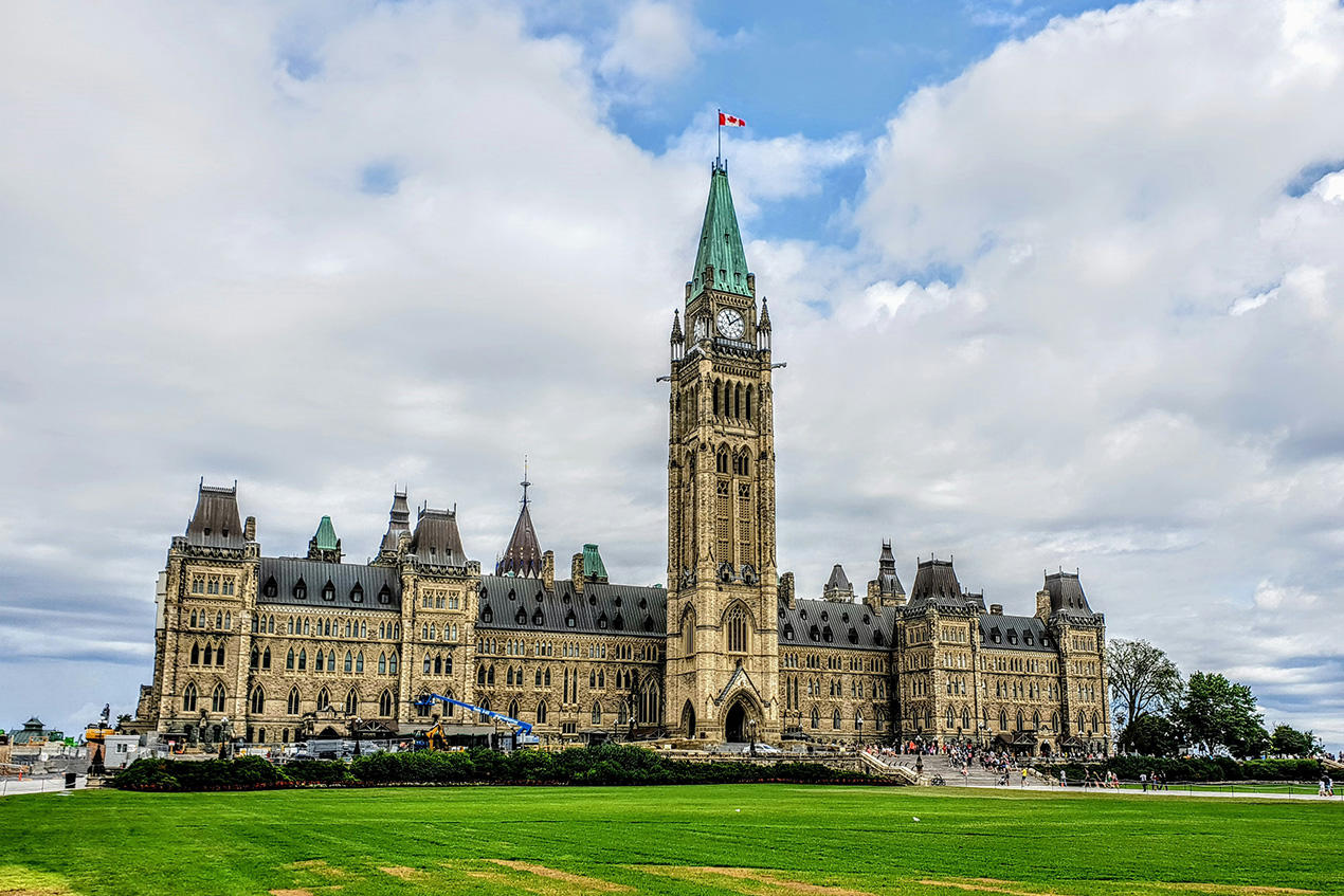 Une pente herbeuse sur la colline du Parlement avec les Chambres du Parlement et la Tour de la Paix en arrière-plan.