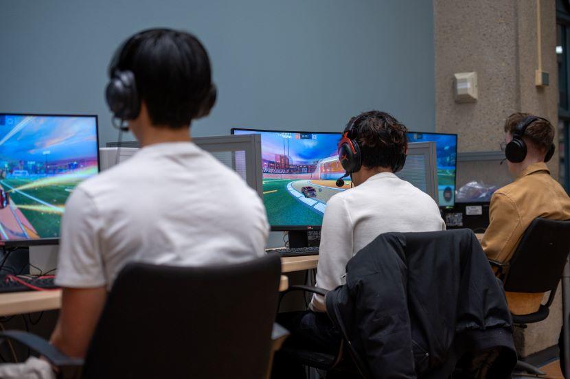 Trois étudiants jouent à des jeux vidéo.