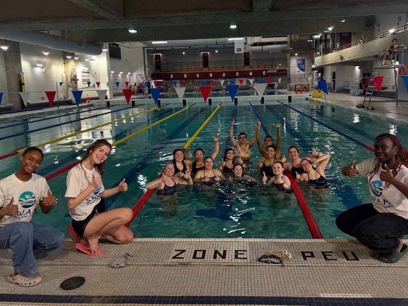 Un groupe d'étudiants bénévoles du club SWAM lèvent le pouce et applaudissent dans la piscine de l'Université d'Ottawa.