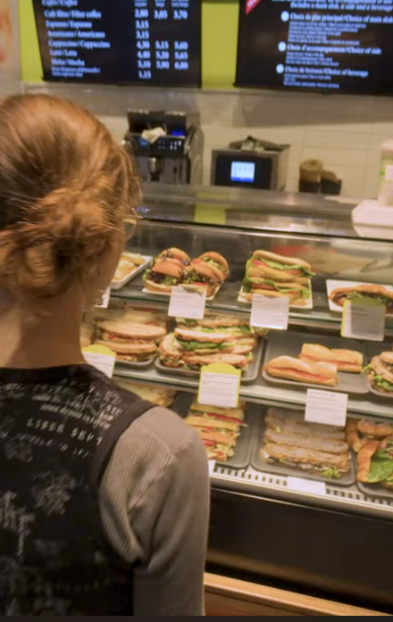 une étudiante qui commande un sandwich dans un point de service alimentaire