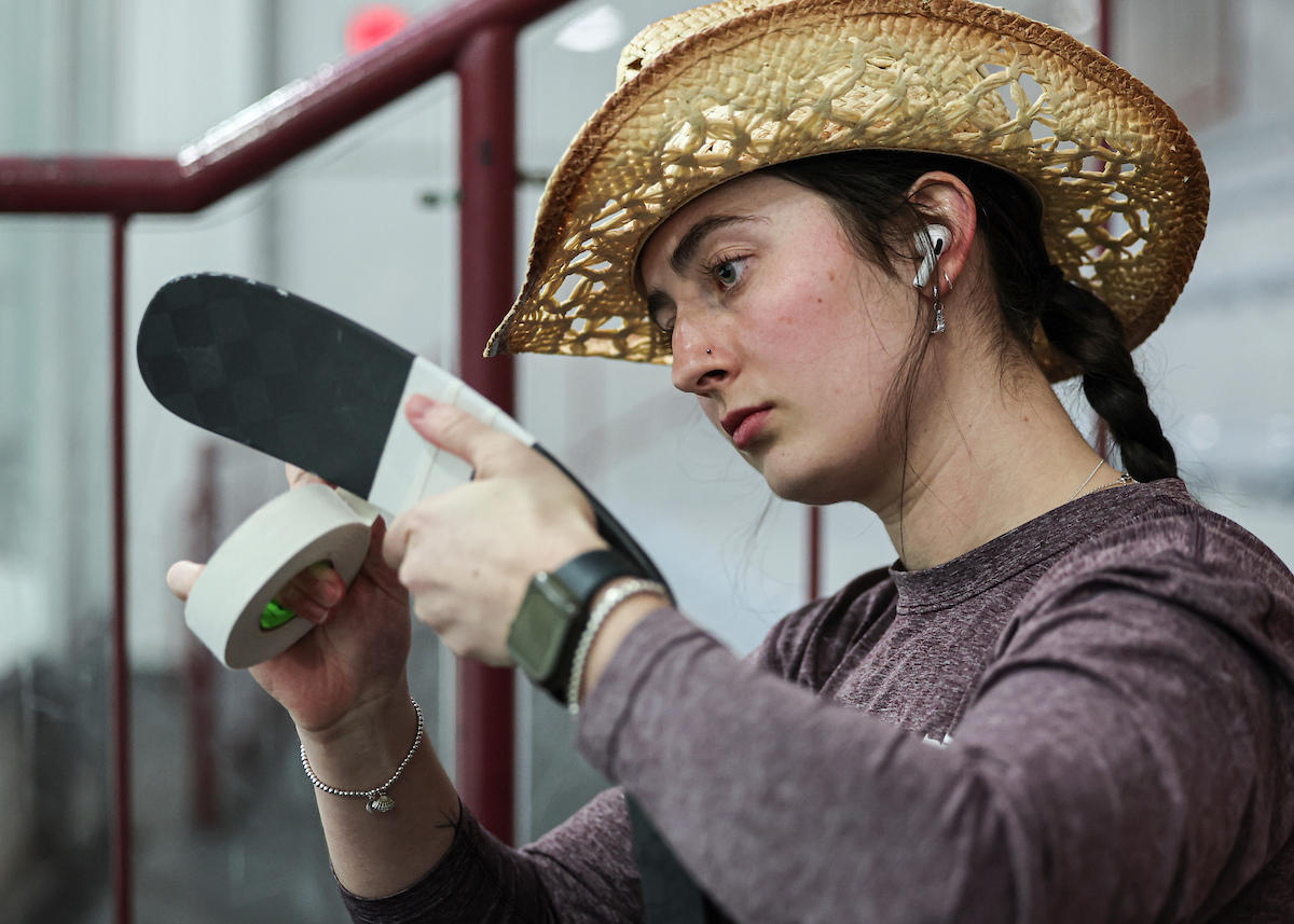 Une joueuse de hockey des Gee-Gees scotche son bâton de hockey avec un chapeau de cow-boy sur la tête.