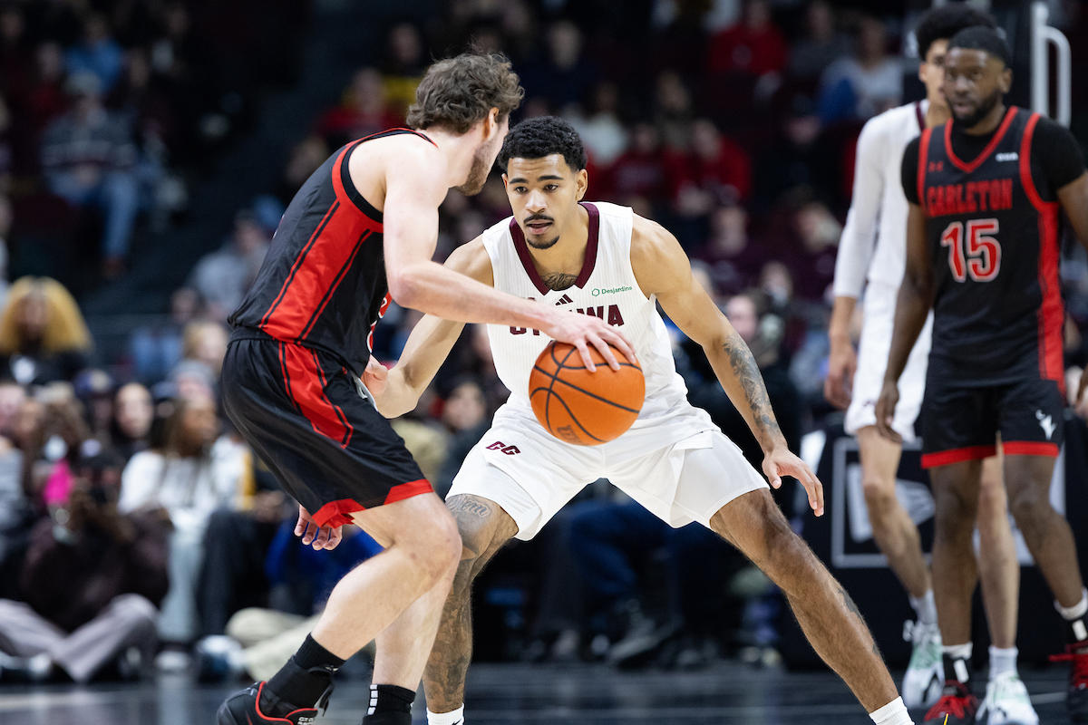 Un joueur de basket-ball masculin des Gee-Gees face à un joueur de basket-ball masculin des Ravens de Carleton qui est en possession du ballon