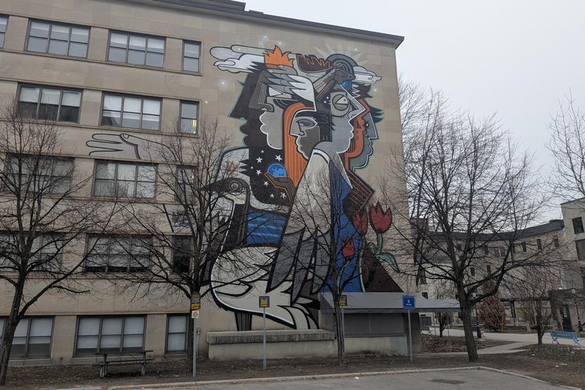 Une fresque murale composée de visages abstraits.