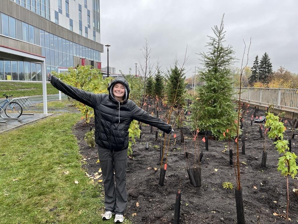  Une étudiante souriante se tenant à côté de la microforêt