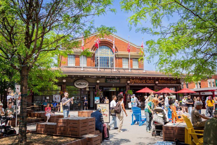 Des personnes assises à des tables à l'extérieur du bâtiment du Byward Market.
