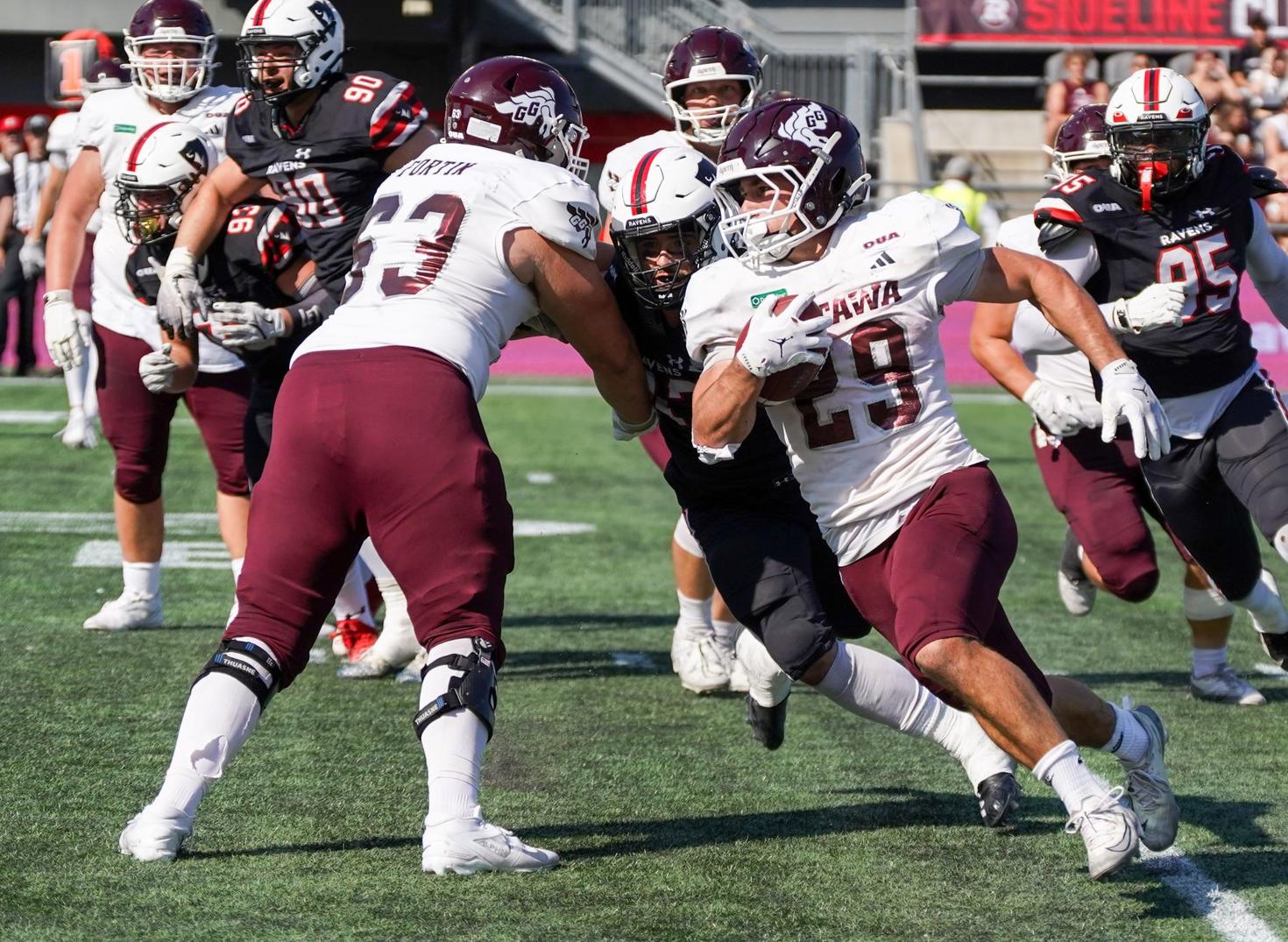 Les joueurs de football masculin des Gee-Gees s'élancent avec le ballon au place TD lors du Match Panda en 2025.